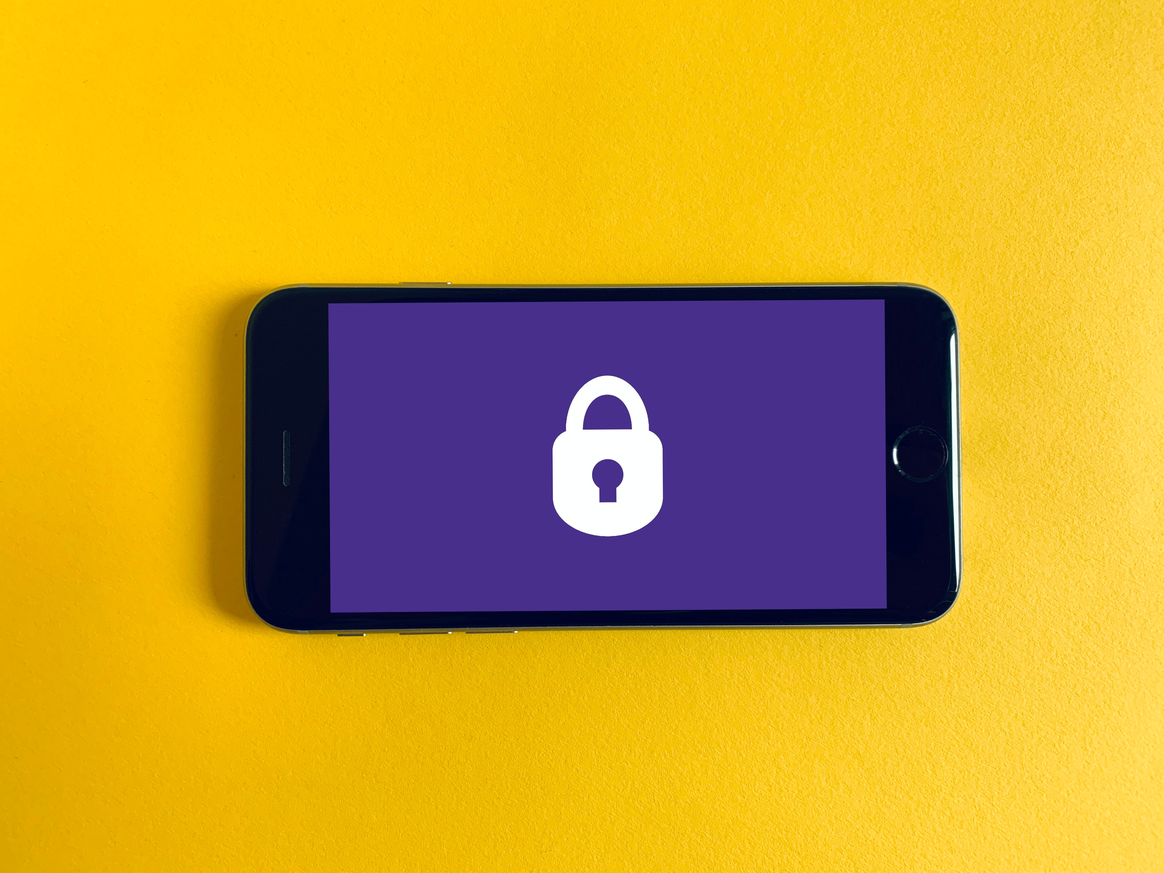 phone with lockpad and purple screensaver over a yellow background 